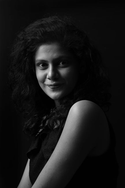 Monochrome portrait of a smiling woman in a studio setting, exuding elegance and charm.