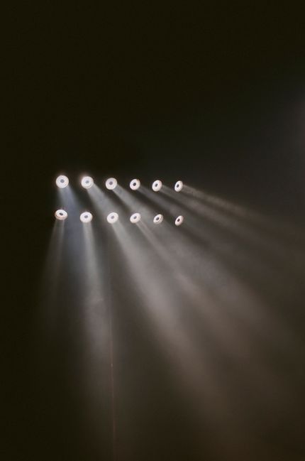 Row of stage lights cutting through haze — photo by Isabella Mendes on Pexels