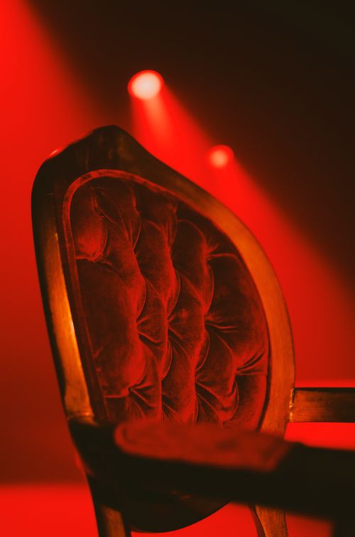 Free An elegant vintage chair illuminated by bold red lighting, creating a dramatic atmosphere. Stock Photo