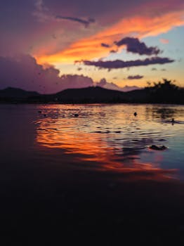 Stunning sunset reflection over water with vibrant colors and dramatic sky in Holguín, Cuba.
