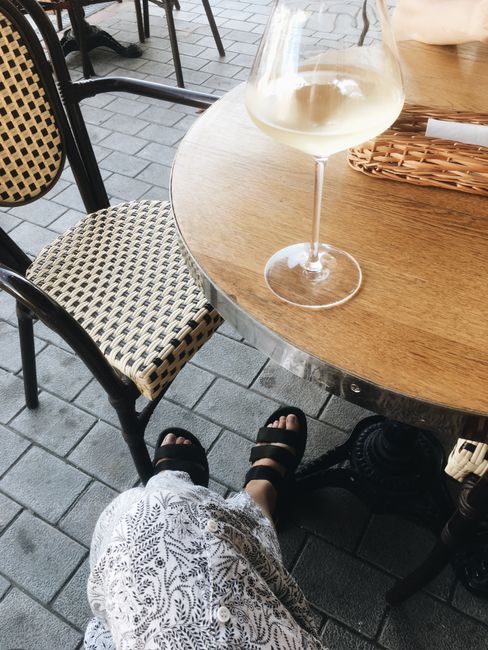 Charming outdoor cafe setup with a glass of white wine on a wooden table.