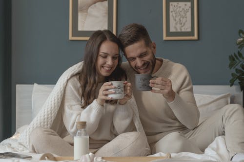 Couple Smiling while Having Their Breakfast in Bed