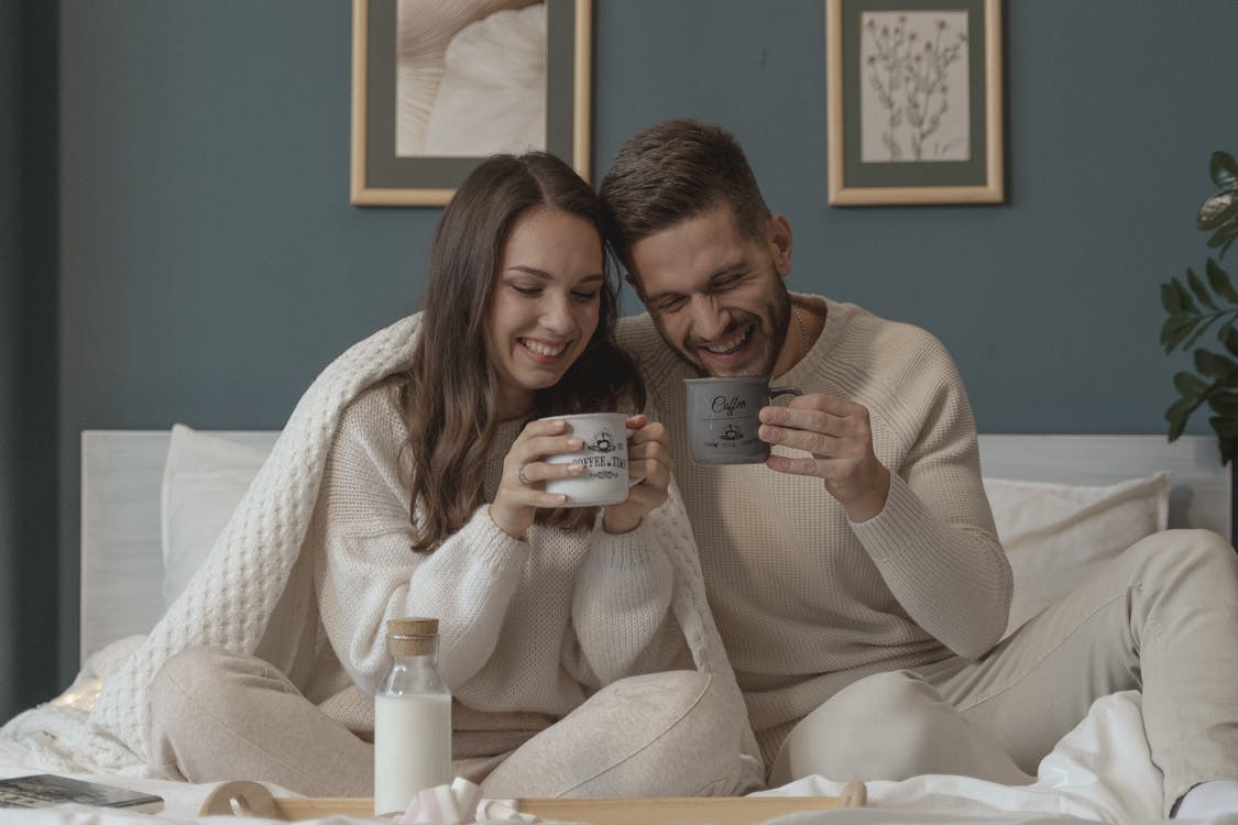 Free Couple Smiling while Having Their Breakfast in Bed Stock Photo