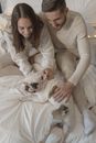 幸福的夫妇在室内舒适的床上，享受着法国斗牛犬带来的放松时刻