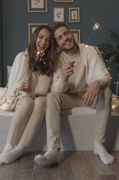 一对穿着冬装的幸福夫妇在家里庆祝新年，欣赏烟火