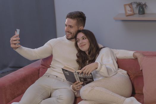 一对夫妇在沙发上放松，一边用智能手机自拍，一边分享舒适的时刻