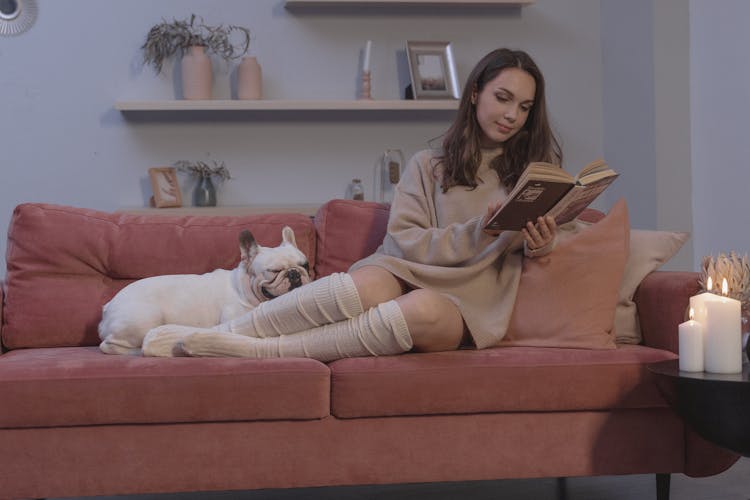 Woman Sitting On Couch While Reading A Book