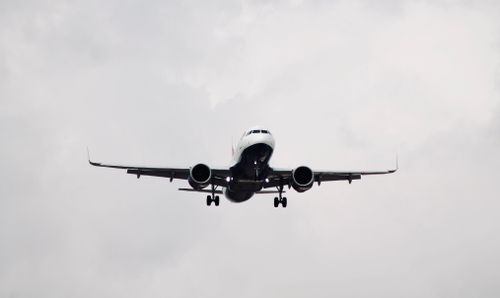 Free A commercial airplane captured in flight against a cloudy backdrop. Stock Photo