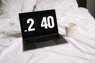 Black and Silver Laptop Computer Beside White Ceramic Mug on White Textile