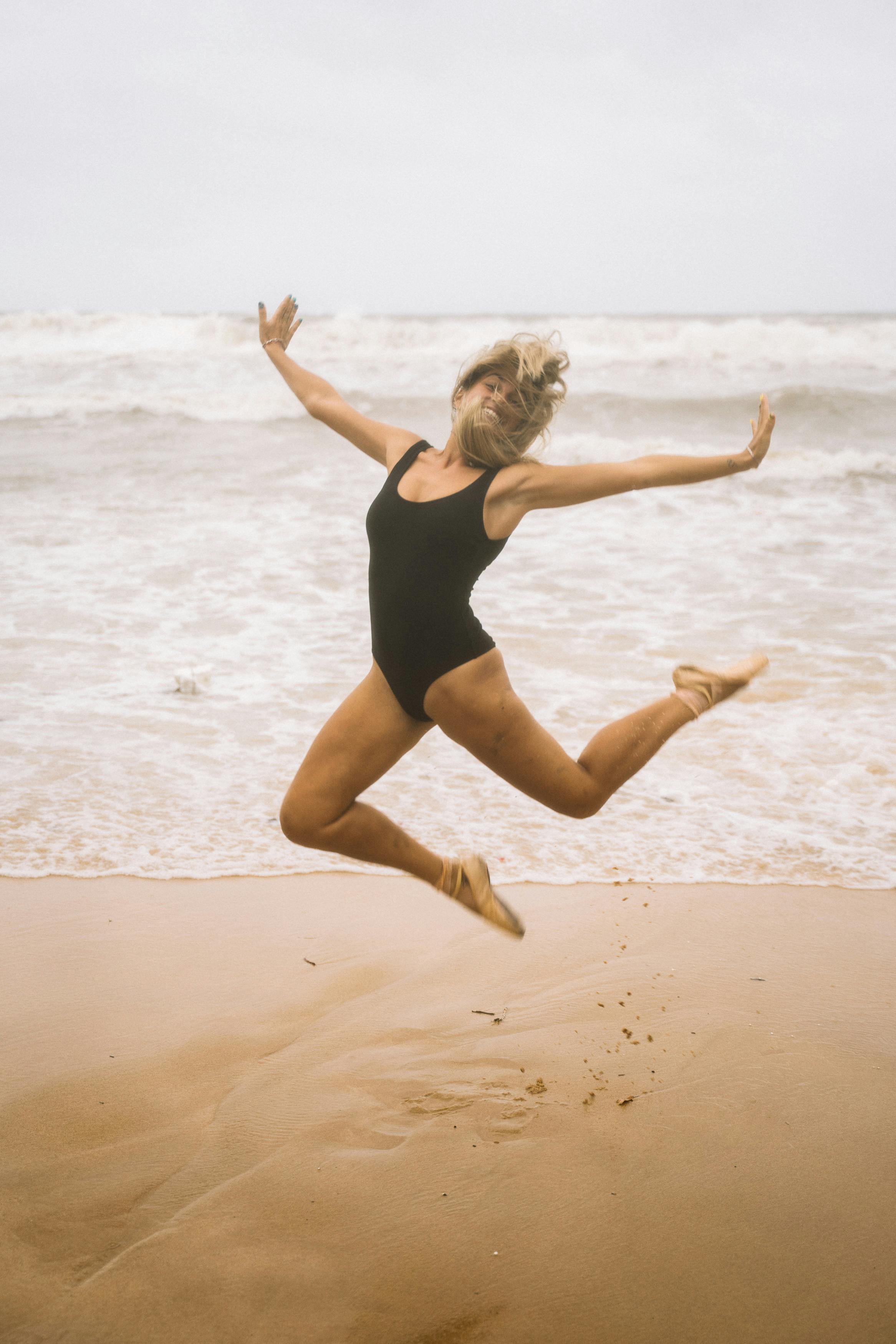 woman in swimsuit jumping on beach