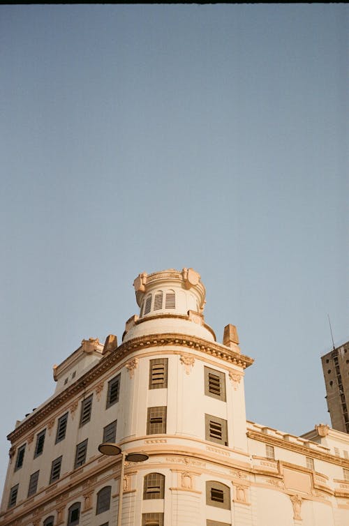 Low angle of aged multistage house facade with windows under blue sky in town