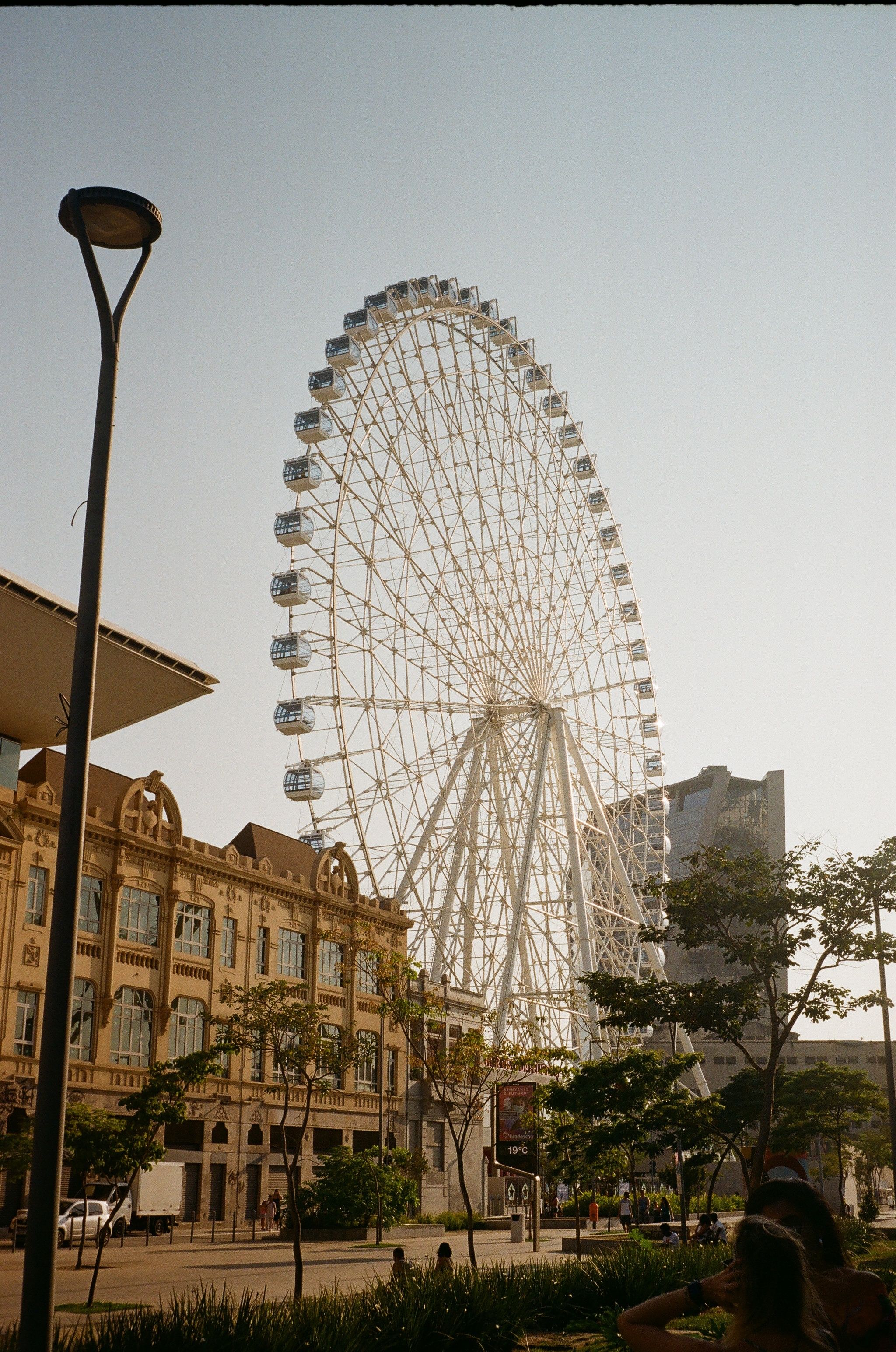 Low angle of big observation wheel near old house facade under sky in town