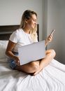 高加索女人在家使用智能手机和笔记本电脑时露出了微笑