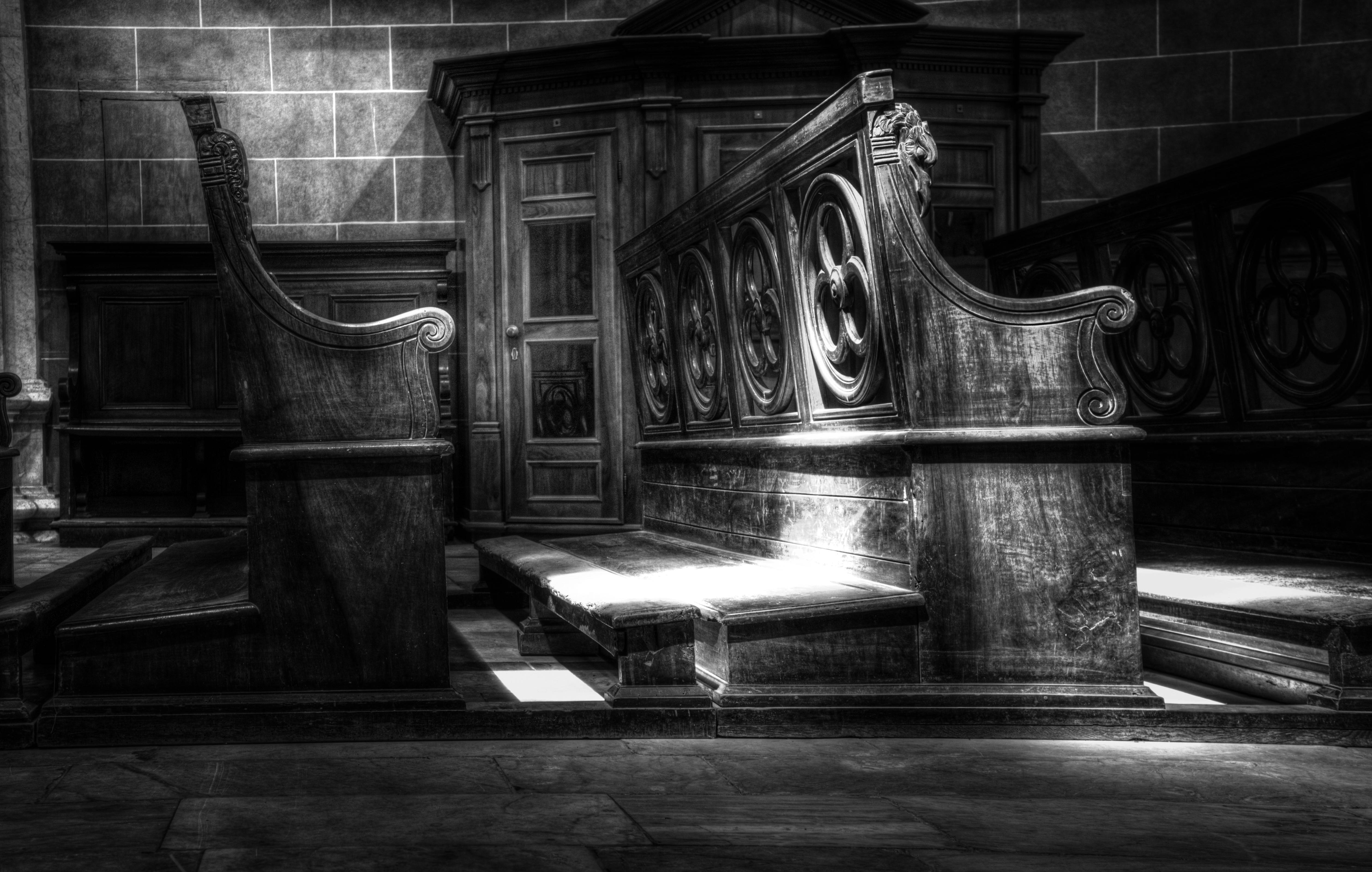 单色灯光照亮了复杂的木制教堂长凳，展现出神圣的建筑之美