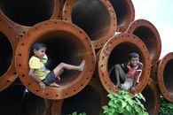 Boys Sitting in Huge Brown Steel Pipes