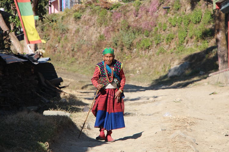 Elderly Woman Walking Alone While Holding A Stick