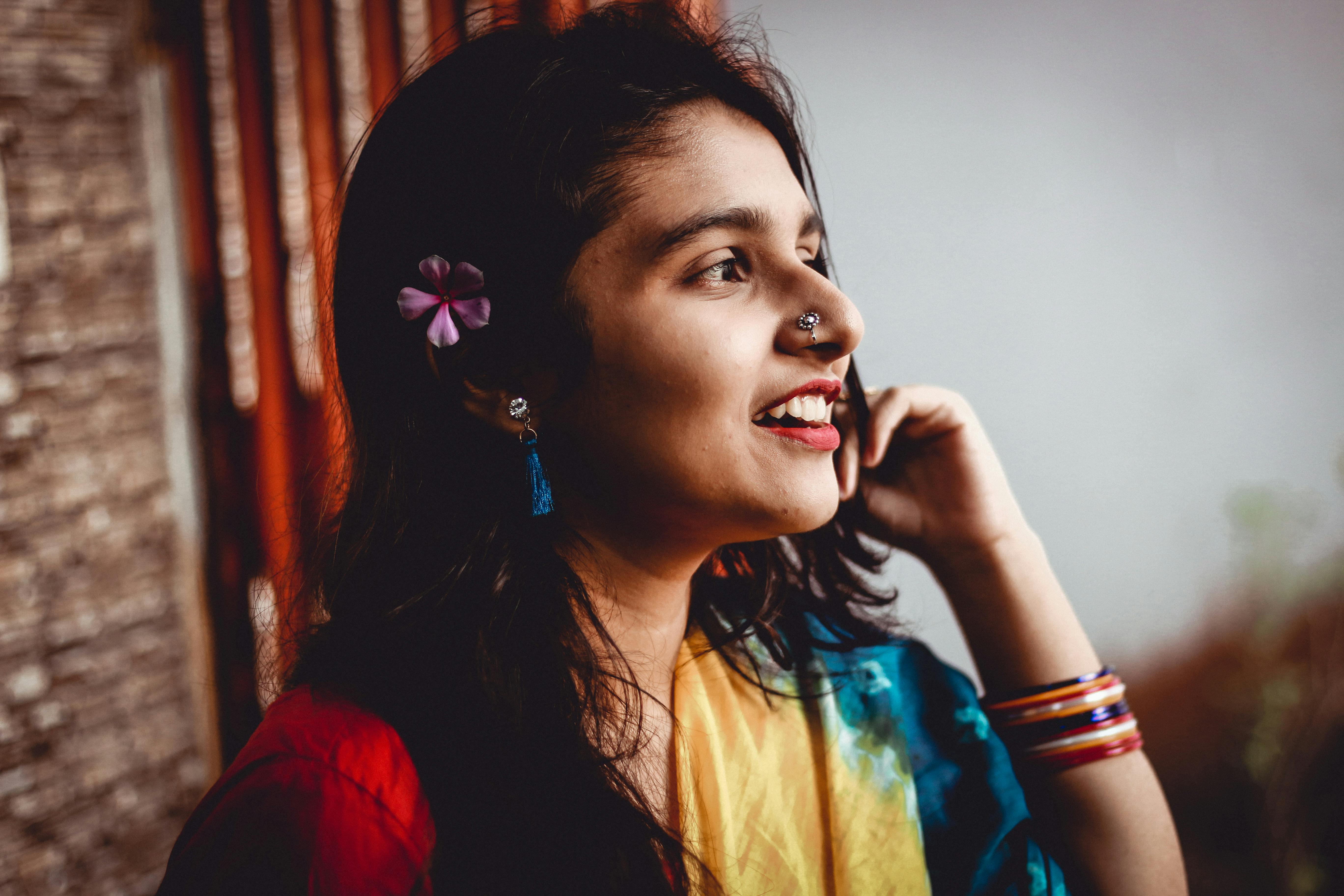 Cheerful woman with colorful sari and flower in hair, enjoying the outdoors.