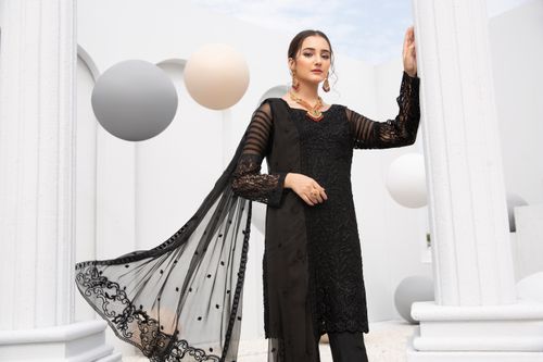 Free Elegant woman posing in a traditional black dress with modern earrings and makeup against a contemporary backdrop. Stock Photo