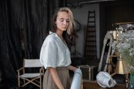 Woman in White Dress Shirt and Brown Skirt Standing Near Brown Wooden Chair