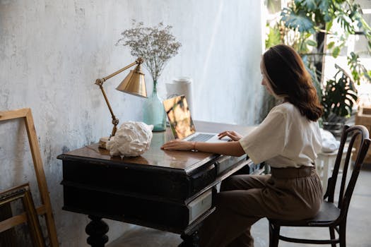 A woman using a laptop at a wooden desk in a stylish home office setting.