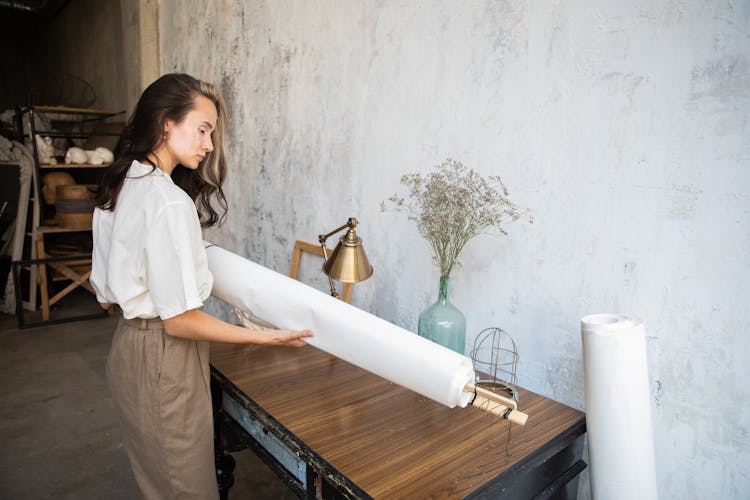 Woman Holding A Roll Of Paper In An Art Studio