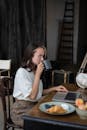 Woman in White Shirt Sitting on Chair Using Macbook