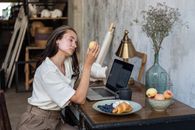 Woman Holding Fruit by Laptop in Art Studio