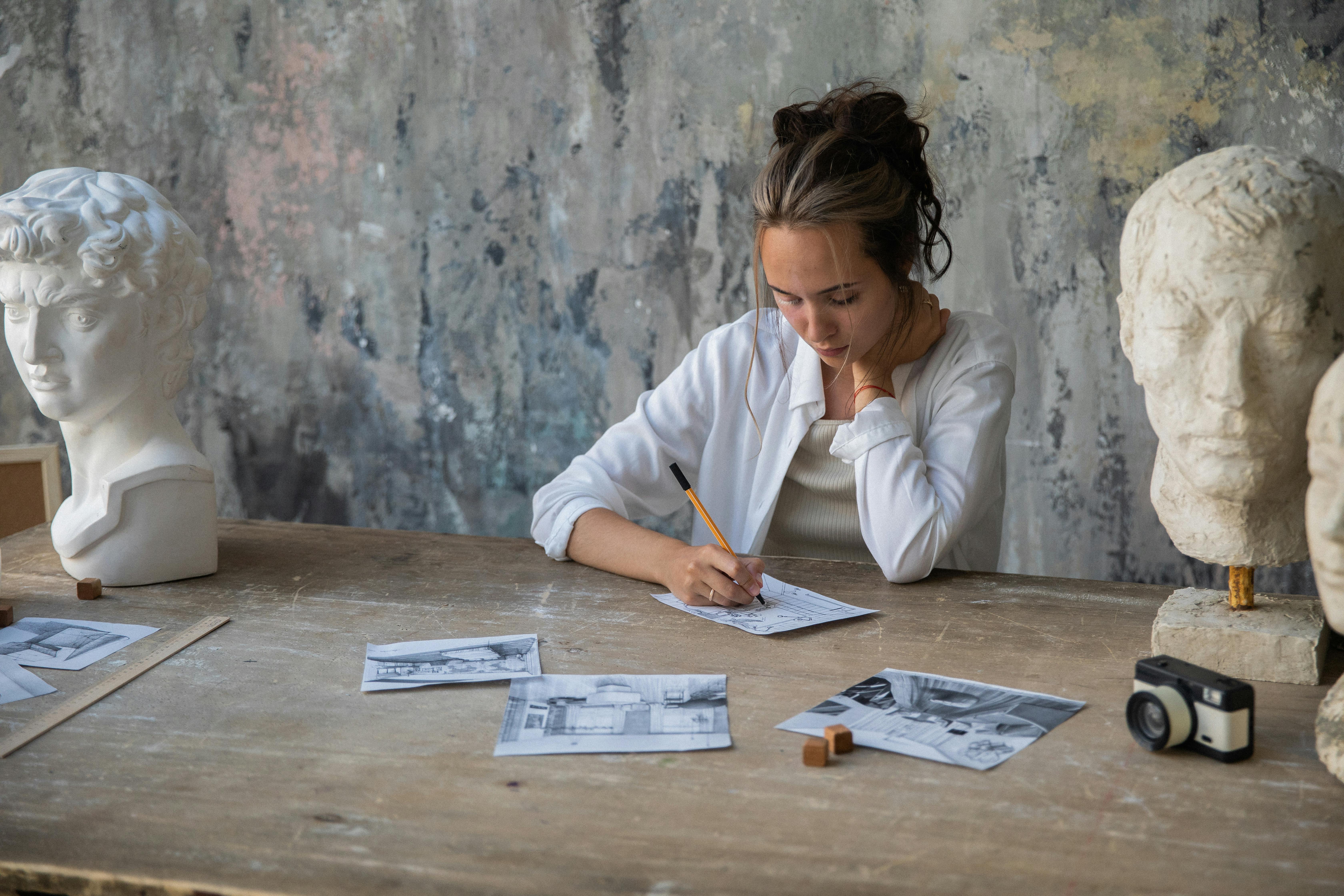 一位女艺术家在创意工作室里，正对着石膏胸膜素描，以此培养创造力