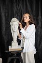Woman in White Top Standing Beside a Sculpture