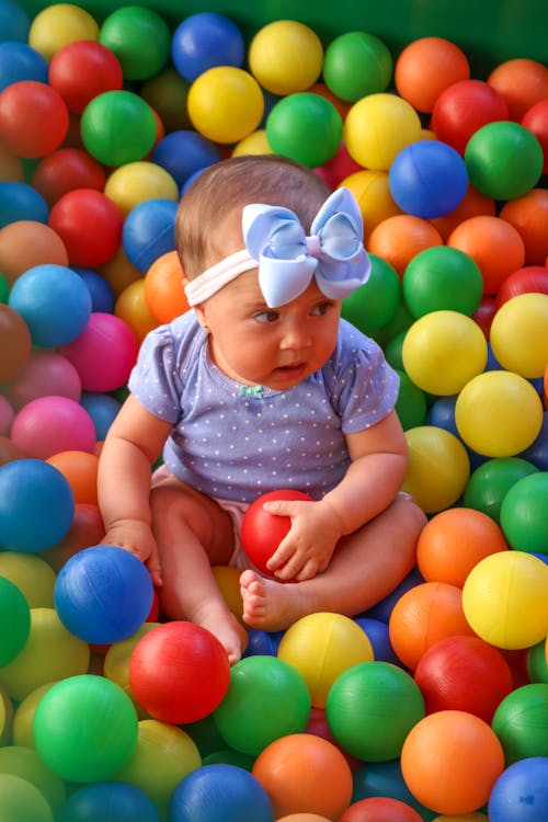 Free  Cute Baby in Blue and White Polka Dot Shirt Surrounded by Plastic Balls Stock Photo