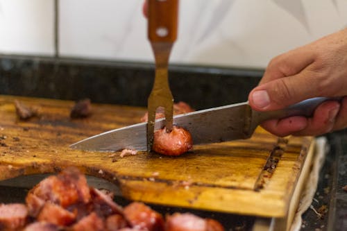 Free Person Slicing Sausage on Wooden Chopping Board Stock Photo