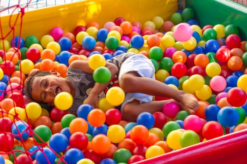 Free A happy child laughing and playing in a colorful ball pit filled with multicolored balls. Stock Photo