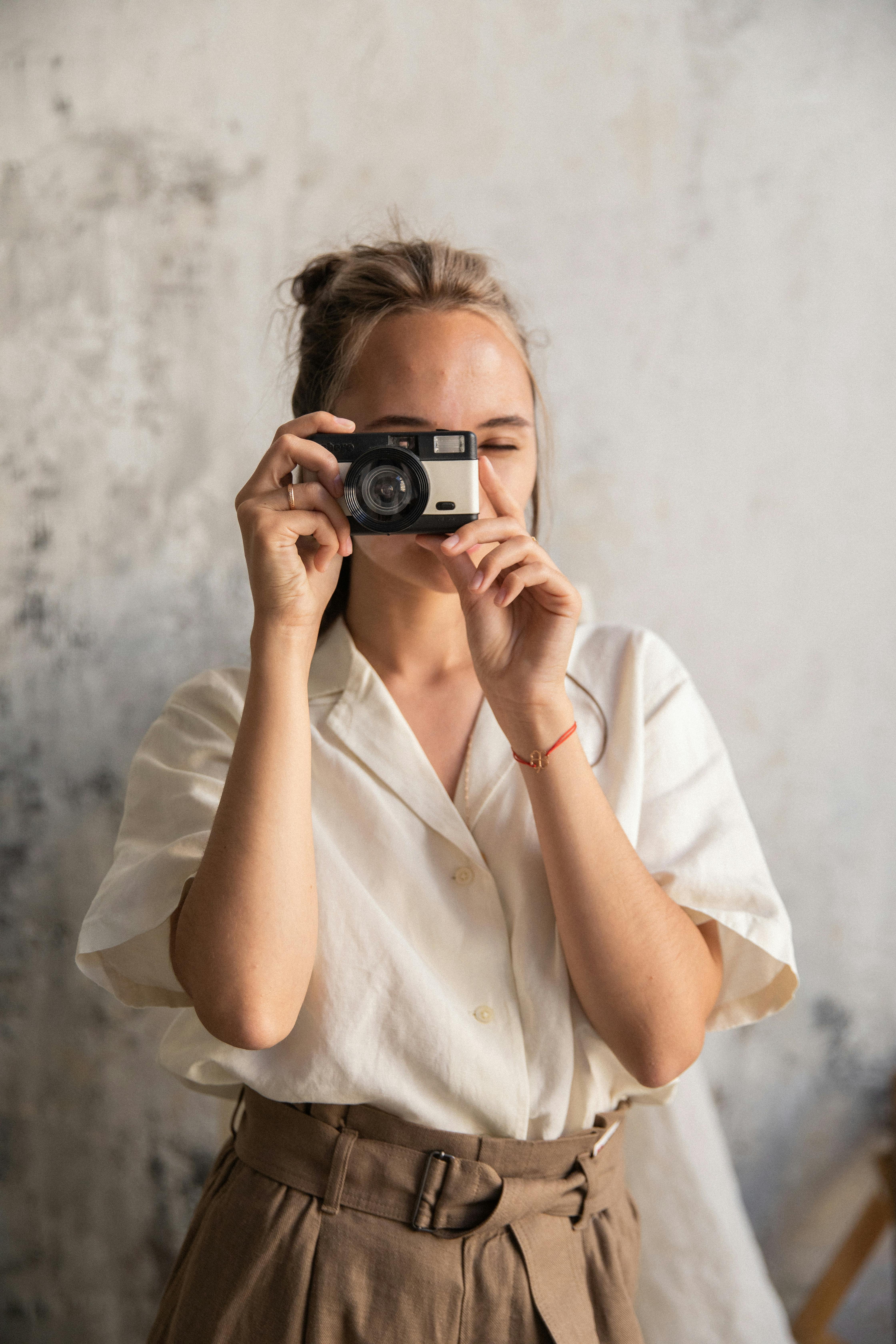 a woman in white top and brown pants taking photos