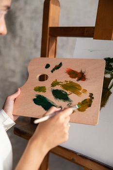 艺术家在木制调色板上混合鲜艳的色彩，在画布上作画