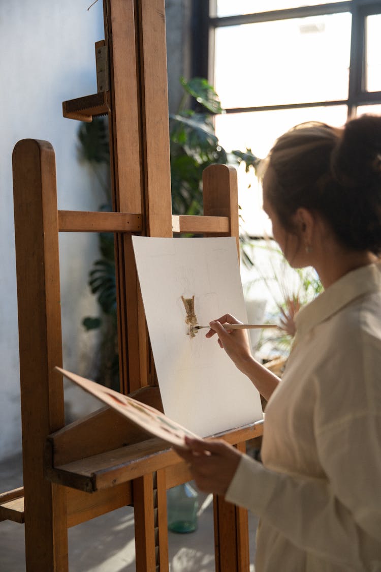 Woman In White Dress Shirt Painting On A Canvas