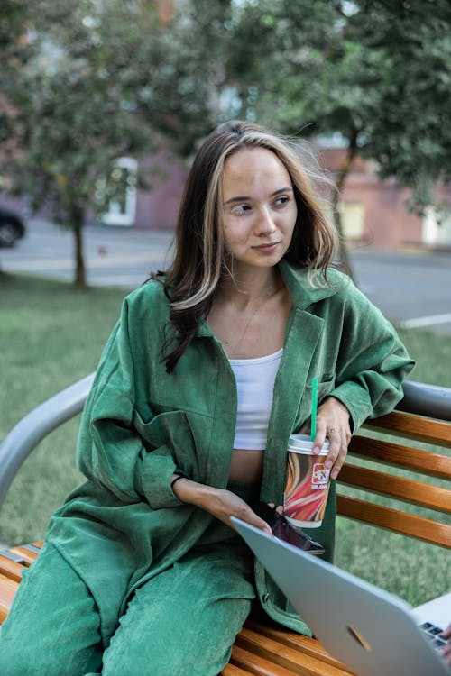 Woman in Green Blazer Sitting on Wooden Bench