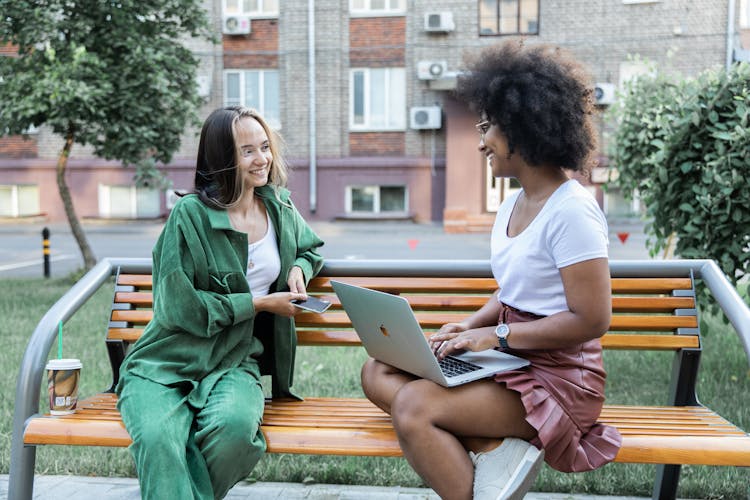 Two Women Sitting On A Bench Hanging Out Together