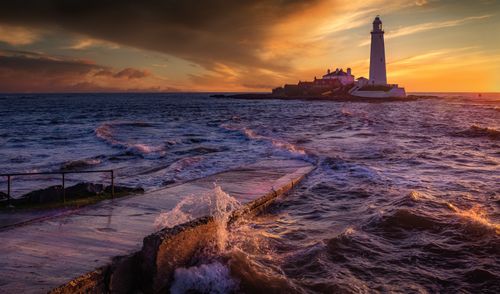 Free Stunning sunset view of St Mary's Lighthouse with crashing waves in Whitley Bay, UK. Stock Photo