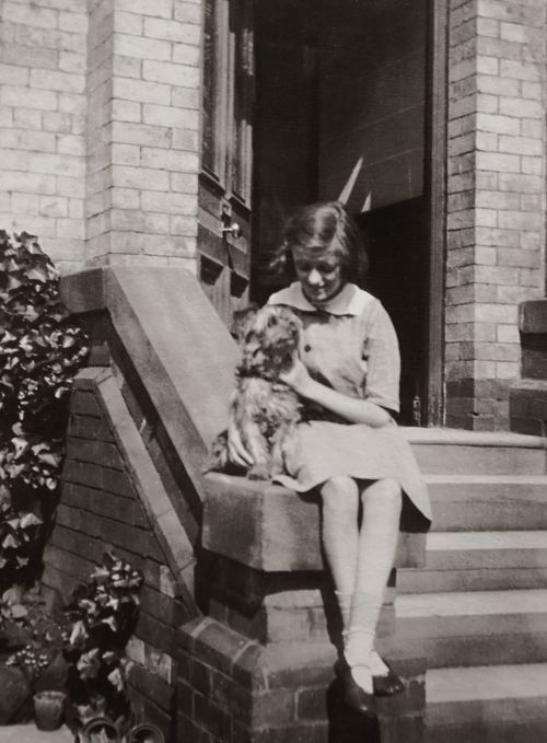 Free A young girl sits on a doorstep with her dog in a classic vintage black and white photo. Stock Photo