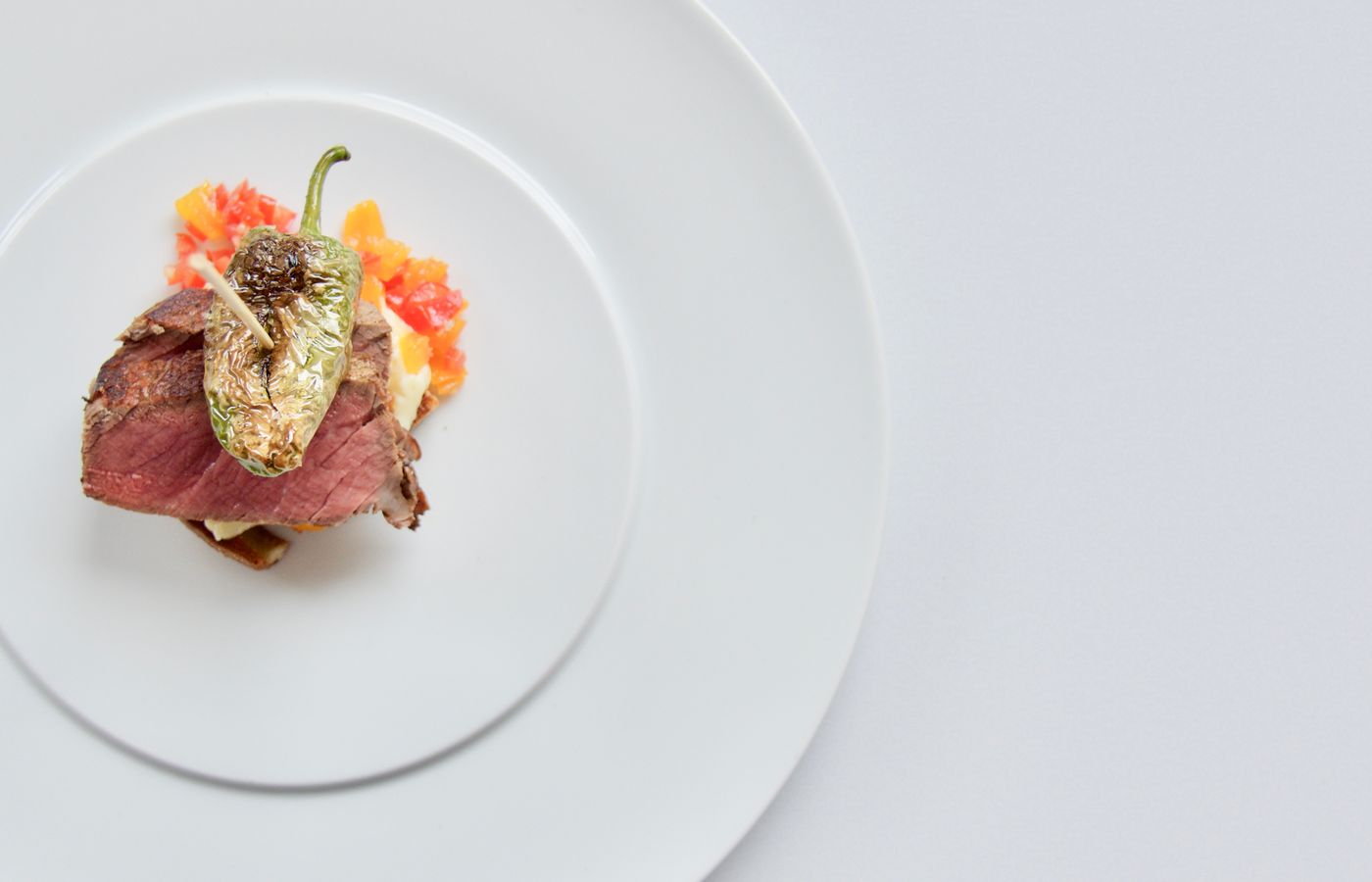 Elevated culinary presentation of beef served with a roasted pepper. Perfect for gourmet dining and cuisine enthusiasts.