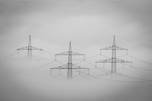 Grayscale Photo of Electric Post Cloaked by the Dense Fog