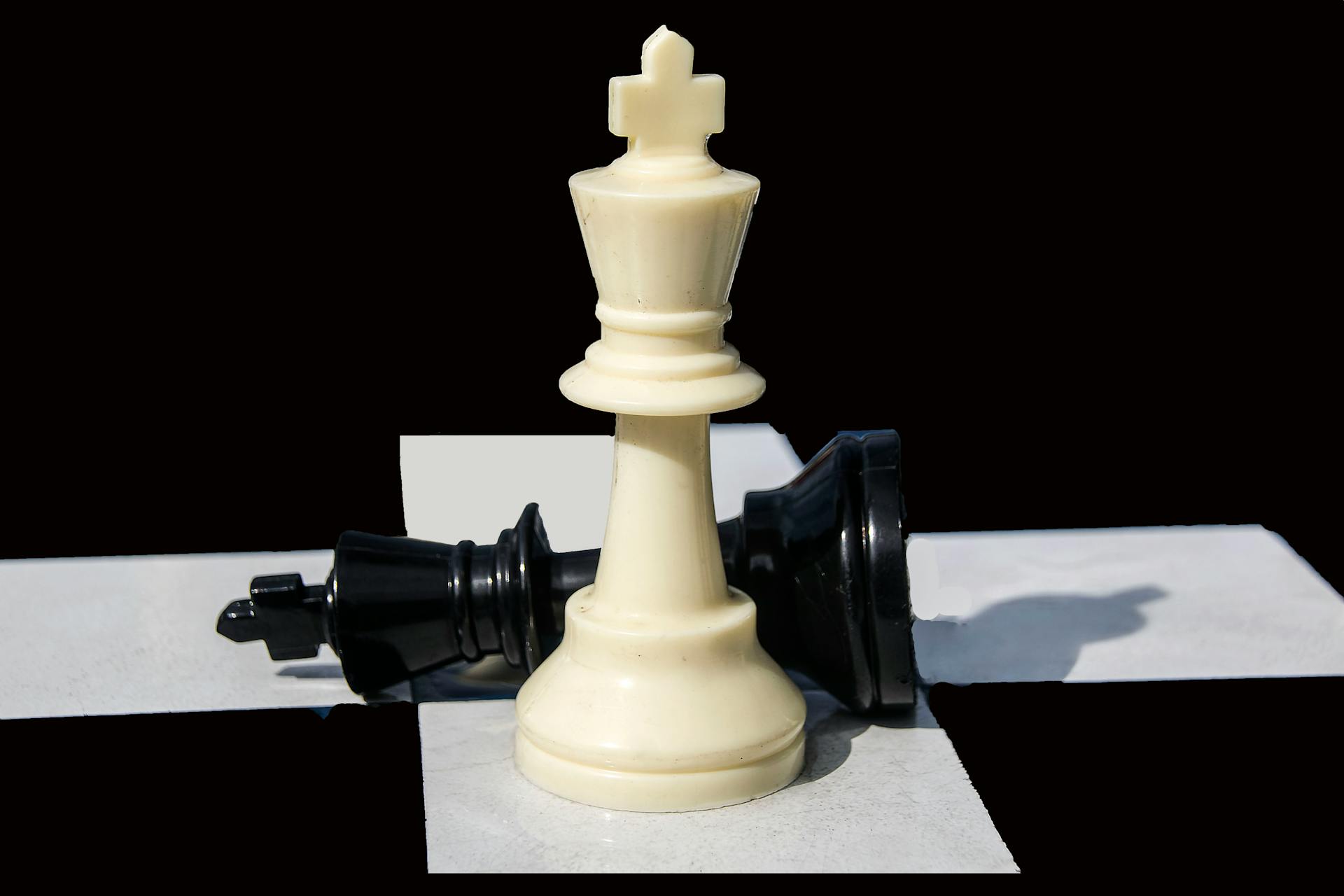 Close-up of white king and fallen black knight on a chessboard highlighting strategy.