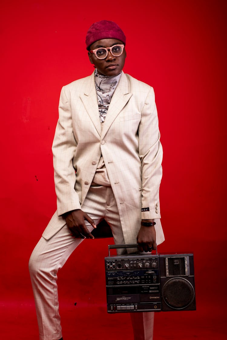 Man In White Suit Standing While Holding An Old Radio