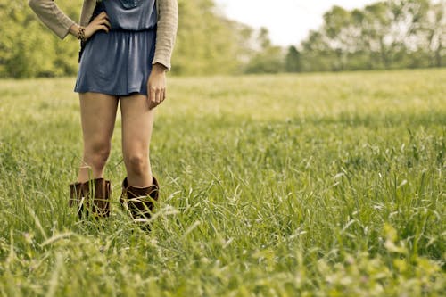 Person Wearing Brown Boots Standing on Green Grass Ground