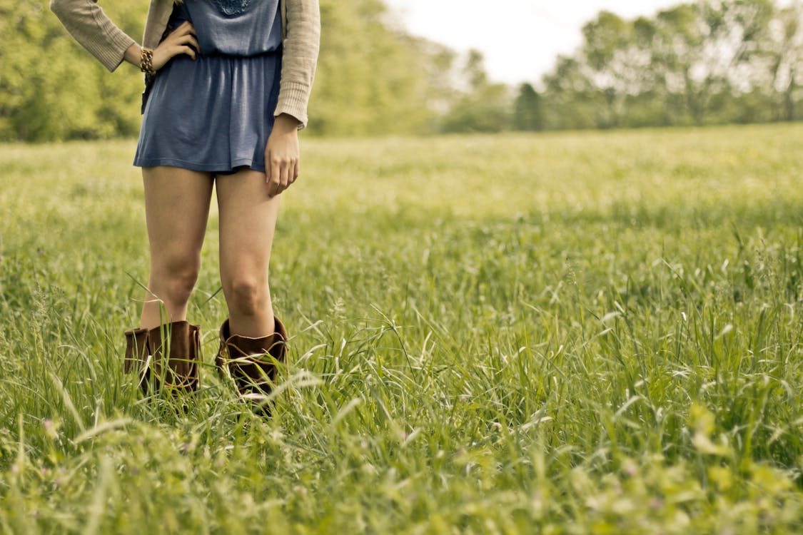 緑の芝生の上に立っている茶色のブーツを履いている人