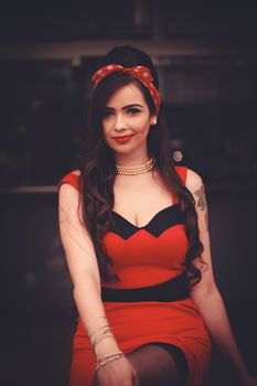 Woman in red dress with retro pin-up style, posing indoors. Timeless fashion vibe.