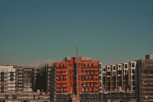 Modern construction site with scaffolding against a clear blue sky.