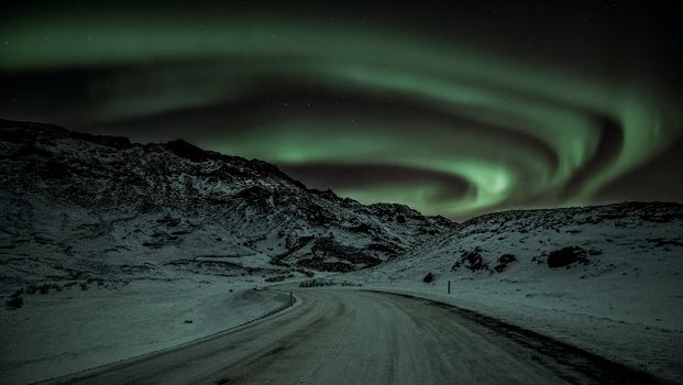夜晚，北极光的壮丽景色照亮了冰岛的雪山