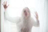 Woman Behind a Net Curtain