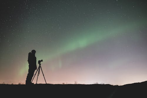 Sylwetka Człowieka Stojącego Na Skale Pod Zielonym Niebem Z Gwiazdami